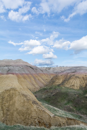 Layers of sandstone ranging from yellow to red to white rest under a cloudy sky.の写真素材