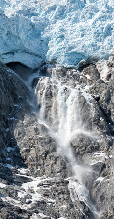 Water liberated by the heat of the day gushing from under a blue white glacier.の写真素材