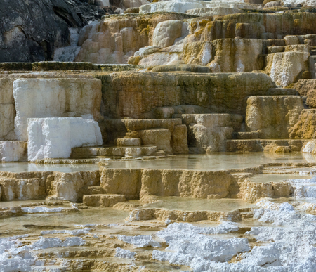 Water stands stilly in pools surrounded by white and tan rock.の写真素材