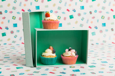 Happy Birthday day cupcake and cake bakery with candles, bright lights bokeh. Background holiday with confetti, balloon and place for text.の写真素材