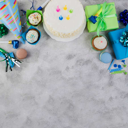 Happy Birthday day cupcake and cake bakery with candles, bright lights bokeh. Background holiday with confetti, balloon and place for text.の写真素材