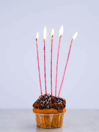 Happy birthday day cake or cupcake with candles and light. Background with place for text.