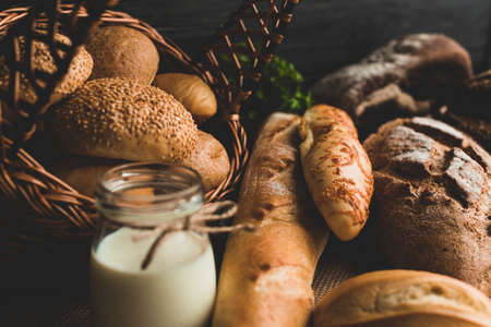 Different baking buns, croissants, gingerbread cookies. Delicious freshly baked bread on wooden background with place for text. Fresh loaves of bread And sliced ââbreads containing sesame seeds.の写真素材