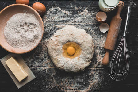 Beat flour and kitchen utensils, a baking dish, a rolling pin with eggs on the table. Baking, cooking concept. Chef making bread and gingerbread cookies. The cook kneads and rolls the dough.の写真素材