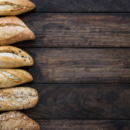 Different baking buns, croissants, gingerbread cookies. Delicious freshly baked bread on wooden background with place for text. Fresh loaves of bread And sliced ââbreads containing sesame seeds.の写真素材