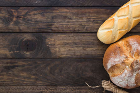 Different baking buns, croissants, gingerbread cookies. Delicious freshly baked bread on wooden background with place for text. Fresh loaves of bread And sliced ââbreads containing sesame seeds.の写真素材