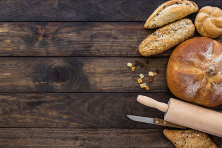 Different baking buns, croissants, gingerbread cookies. Delicious freshly baked bread on wooden background with place for text. Fresh loaves of bread And sliced ââbreads containing sesame seeds.の写真素材