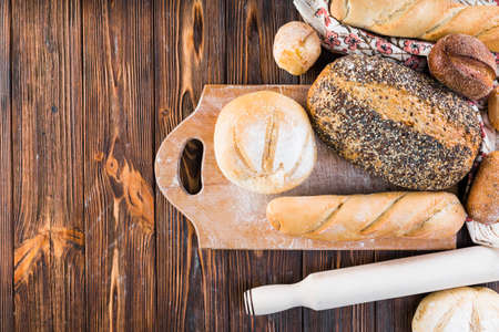Different baking buns, croissants, gingerbread cookies. Delicious freshly baked bread on wooden background with place for text. Fresh loaves of bread And sliced ââbreads containing sesame seeds.の写真素材