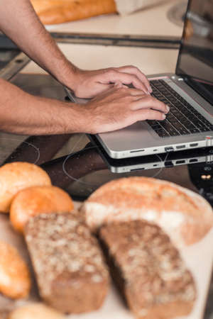 chef working on a laptop on a background of bread