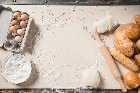 Dough with cookware and roll pin lie on the table, top view.