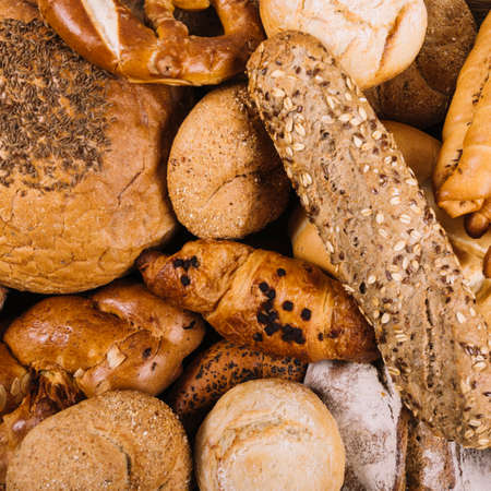 Different baking buns, croissants, gingerbread cookies. Delicious freshly baked bread on wooden background with place for text. Fresh loaves of bread And sliced ââbreads containing sesame seeds.の写真素材