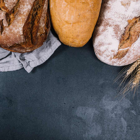 Different baking buns, croissants, gingerbread cookies. Delicious freshly baked bread on wooden background with place for text. Fresh loaves of bread And sliced ââbreads containing sesame seeds.の写真素材