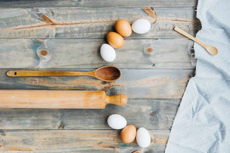 Flour and kitchen utensils whisk, baking dish, rolling pin with eggs on the table. Baking, cooking...