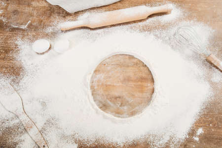 Flour and kitchen utensils whisk, baking dish, rolling pin with eggs on the table. Baking, cooking...