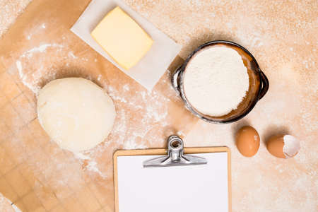 Flour and kitchen utensils whisk, baking dish, rolling pin with eggs on the table. Baking, cooking concept, top view with place for text.の写真素材