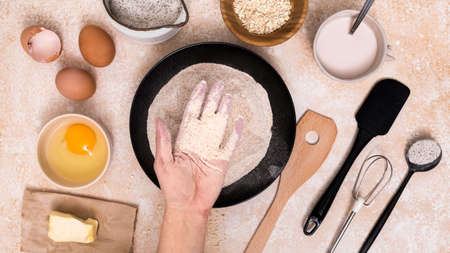 Beat flour and kitchen utensils, a baking dish, a rolling pin with eggs on the table. Baking, cooking concept. Chef making bread and gingerbread cookies. The cook kneads and rolls the dough.の写真素材