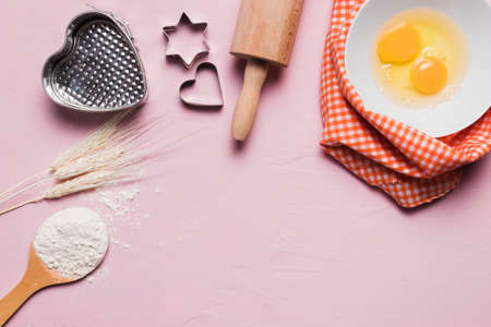 Flour and kitchen utensils whisk, baking dish, rolling pin with eggs on the table. Baking, cooking...
