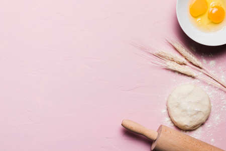Flour and kitchen utensils whisk, baking dish, rolling pin with eggs on the table. Baking, cooking...