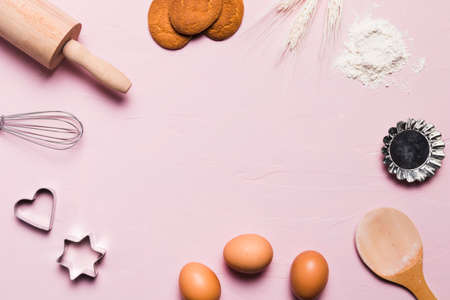 Flour and kitchen utensils whisk, baking dish, rolling pin with eggs on the table. Baking, cooking...