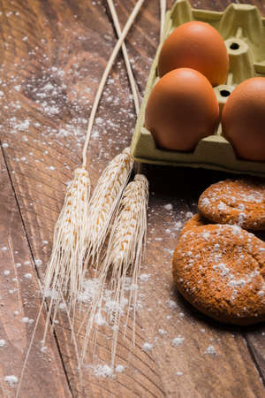 Flour and kitchen utensils whisk, baking dish, rolling pin with eggs on the table. Baking, cooking...