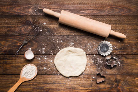 Flour and kitchen utensils whisk, baking dish, rolling pin with eggs on the table. Baking, cooking concept, top view with place for text.の写真素材