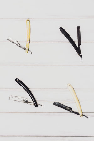 Vintage tools of barber shop on wooden background. Electric hair trimmer, vintage straight razors, a comb, wax and brush on the wooden background, close-up. Place to insert your text. Hipster groomingの写真素材