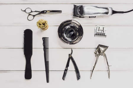 Vintage tools of barber shop on wooden background. Electric hair trimmer, vintage straight razors, a...