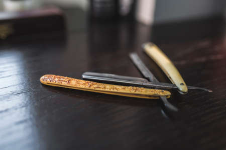 Vintage tools of barber shop on wooden background. Electric hair trimmer, vintage straight razors, a comb, wax and brush on the wooden background, close-up. Place to insert your text. Hipster groomingの写真素材