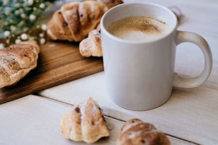 Croissant and cup of coffee on a wooden table with place for text.の写真素材