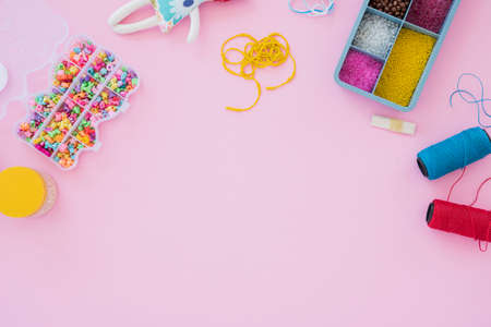 Box with beads, spool of thread, plier and glass to create hand made jewelry on wooden background with place for text. Top viewの写真素材