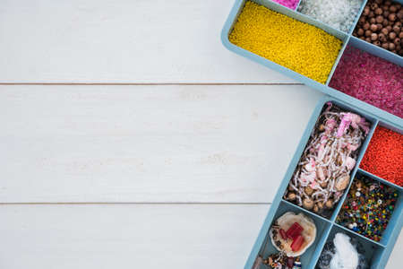 Box with beads, spool of thread, plier and glass to create hand made jewelry on wooden background with place for text. Top viewの写真素材