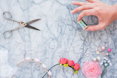 Pair of hands and pliers assembling a bead necklace. Making of handmade jewelery craft. Box with beads on table. Woman hands. Beads and skeins of thread.の写真素材