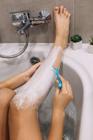 Woman shaves her legs with a razorの写真素材