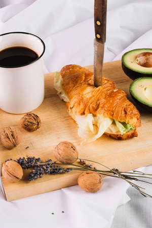 Delicious Breakfast with Croissant sandwiches with Fried Egg, Salad Leaves and avocado. Coffee, healthy breakfast.の写真素材