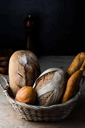 Different baking buns, croissants, gingerbread cookies. Delicious freshly baked bread on wooden background with place for text. Fresh loaves of bread And sliced ââbreads containing sesame seeds.の写真素材