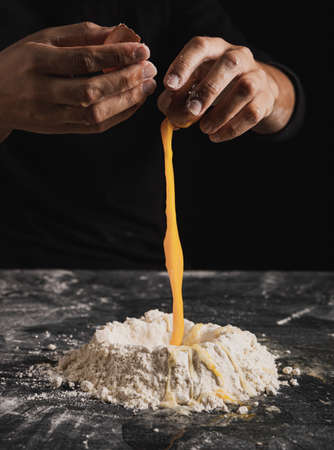 Beat flour and kitchen utensils, a baking dish, a rolling pin with eggs on the table. Baking, cooking concept. Chef making bread and gingerbread cookies. The cook kneads and rolls the dough.の写真素材