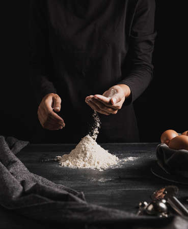 Beat flour and kitchen utensils, a baking dish, a rolling pin with eggs on the table. Baking, cooking concept. Chef making bread and gingerbread cookies. The cook kneads and rolls the dough.の写真素材