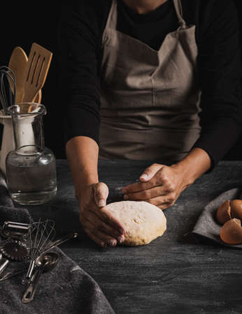 Beat flour and kitchen utensils, a baking dish, a rolling pin with eggs on the table. Baking, cooking concept. Chef making bread and gingerbread cookies. The cook kneads and rolls the dough.の写真素材