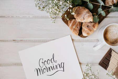 Croissant and cup of coffee on a wooden table with place for text.