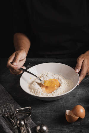 Beat flour and kitchen utensils, a baking dish, a rolling pin with eggs on the table. Baking, cooking concept. Chef making bread and gingerbread cookies. The cook kneads and rolls the dough.の写真素材