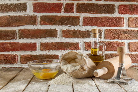 Flour and kitchen utensils whisk, baking dish, rolling pin with eggs on the table. Baking, cooking...