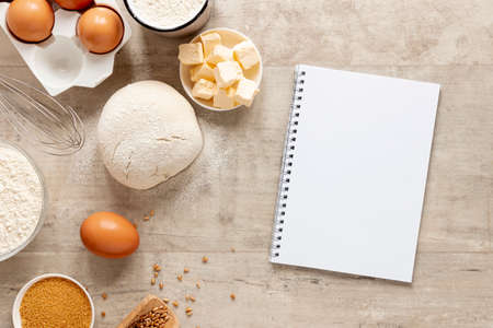 Flour and kitchen utensils whisk, baking dish, rolling pin with eggs on the table. Baking, cooking...