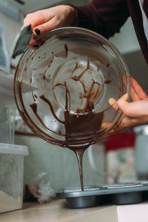 Chef pours melted chocolate from a bowl. Baking conceptの写真素材