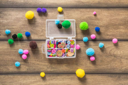 Box with beads, spool of thread, plier and glass to create hand made jewelry on wooden background...
