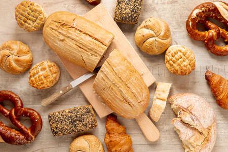 various bakery products with loaf bread and a baker tearing bread