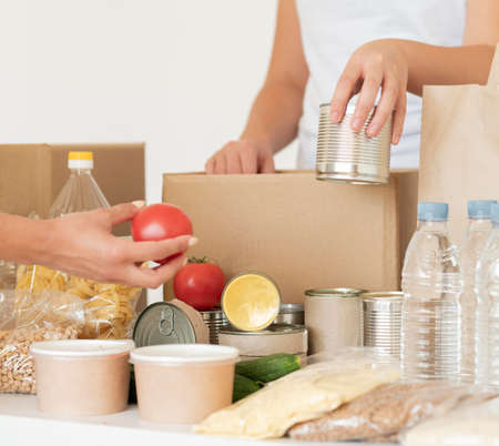 Volunteers putting canned food water donation bag. High quality photoの写真素材