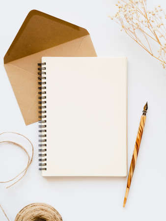 white notebook with wooden nib pale brown envelope with brown thread branch white background. High...