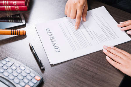Woman pointing document near lady table with calculator smartphone pen. High quality photoの写真素材