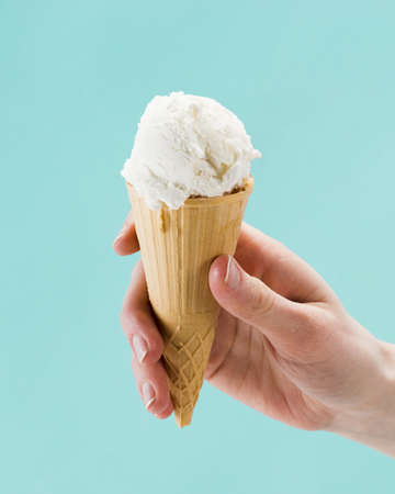 hand holding vanilla ice cream cone blue background. Resolution and high quality beautiful photoの写真素材