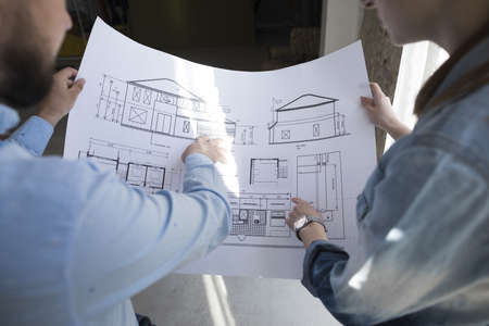 colleagues holding blueprint and discussing on project at office. Resolution and high quality...